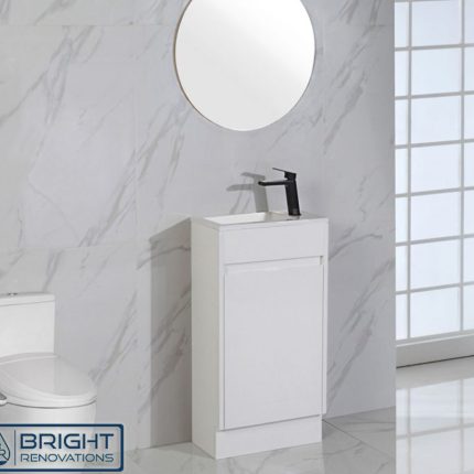 A modern bathroom features a Brant Compact Powder Room Vanity 465 with a round mirror and black faucet. A white toilet is on the left, marble-patterned walls surround, and natural light floods in from a large window. The Bright Renovations logo sits at the bottom left.