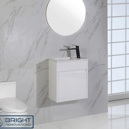 Modern bathroom with marble surfaces features a round mirror, a Brant Compact Powder Room Vanity 465 with black faucet, and a white toilet. Sunlight pours through grid-patterned glass window panels. Logo: Bright Renovations.